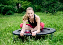 A woman sitting on a mini trampoline rebounder.