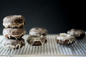 stack of glazed chocolate coconut flour donuts on a wire rack