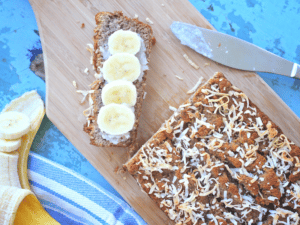 coconut flour banana bread loaf with a slice cut off topped with banana slices and a knife