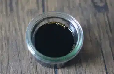 small clear bowl of homemade coconut aminos on a wooden table