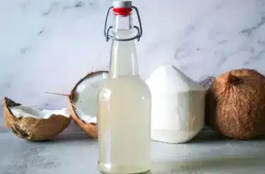 bottle of coconut water kefir with a sliced coconut in the background