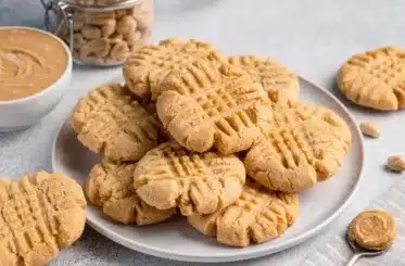 bowl of peanut butter cookies with a bowl of peanut butter and a glass jar of peanuts in the background