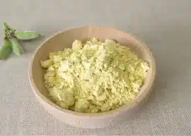 A container of lupin flour alongside a tiny bouquet of green leaves.