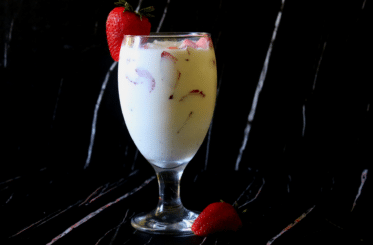 coconut cooler in a glass with strawberry garnish and another strawberry next to it