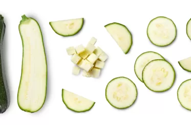A whole zucchini and then various slices of zucchini.