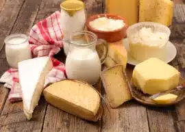 Various cheeses, milk, and cream on a wooden table.