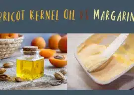 A jar of apricot kernel oil is set with a bowl of apricot kernels, and a basket of apricots. A partially used pot of margarine with a knife stuck in it.