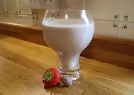 Flavored milk in a glass with a strawberry.