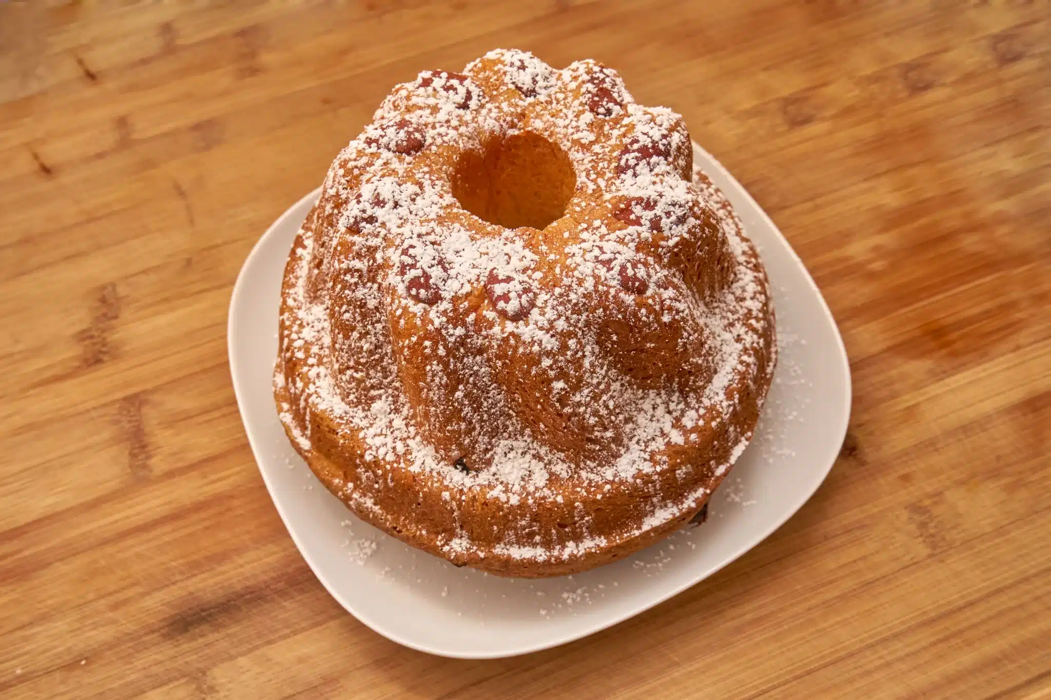 A wooden table featuring a kugelhopf sprinkled with powdered sugar.
