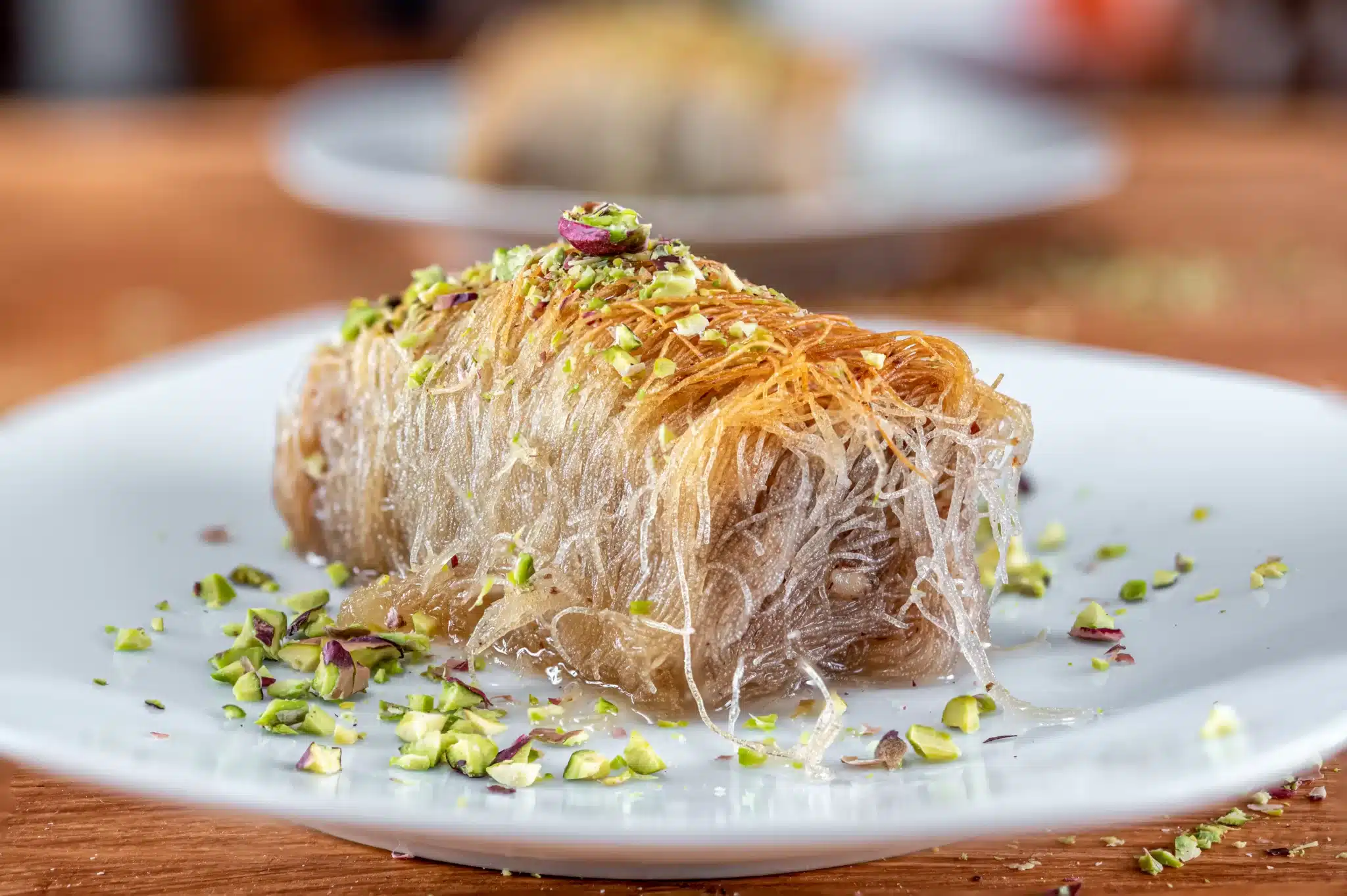 A kataifi served on a plate and sprinkled with pistachio.