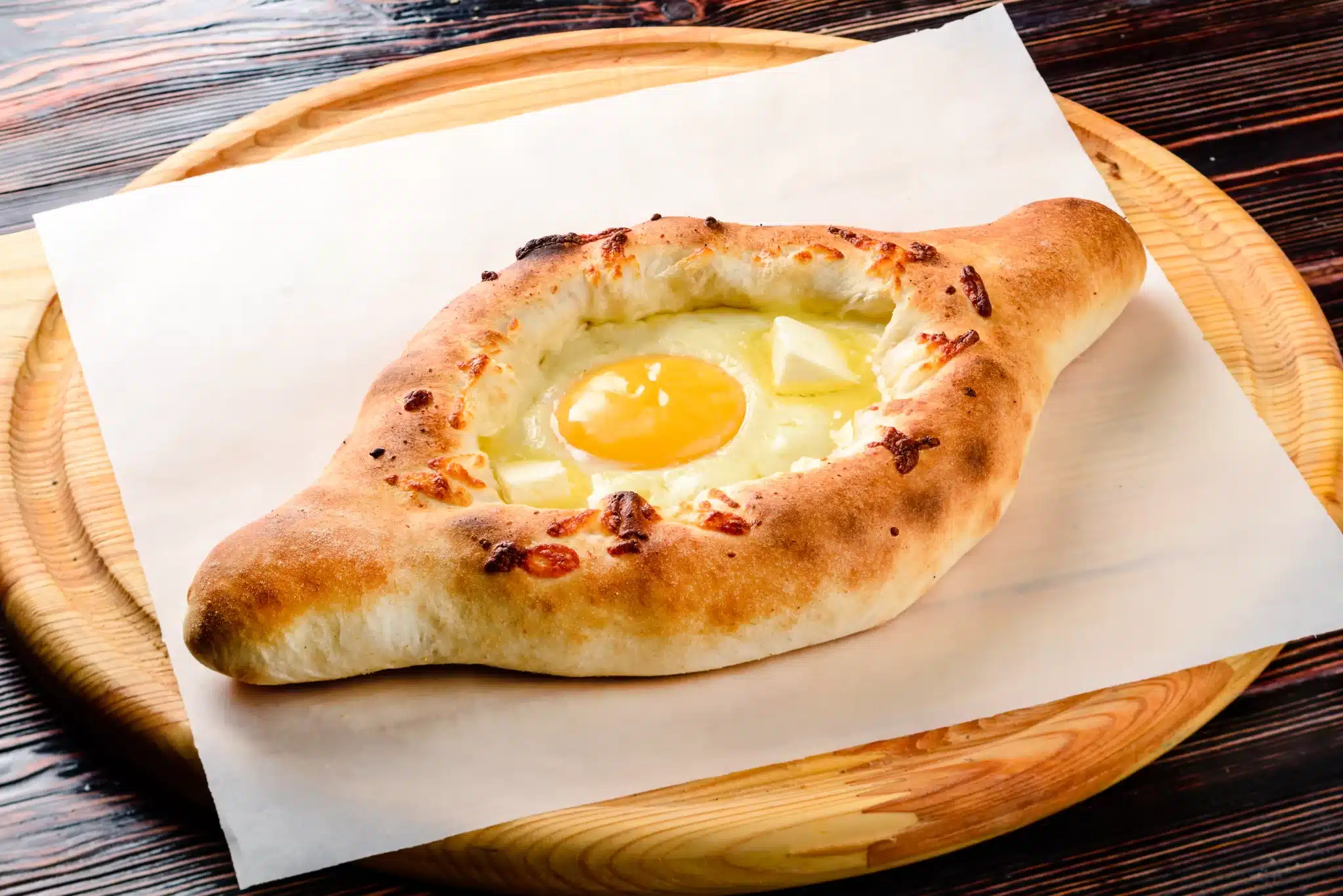 A cutting board displaying a mouthwatering khachapuri.