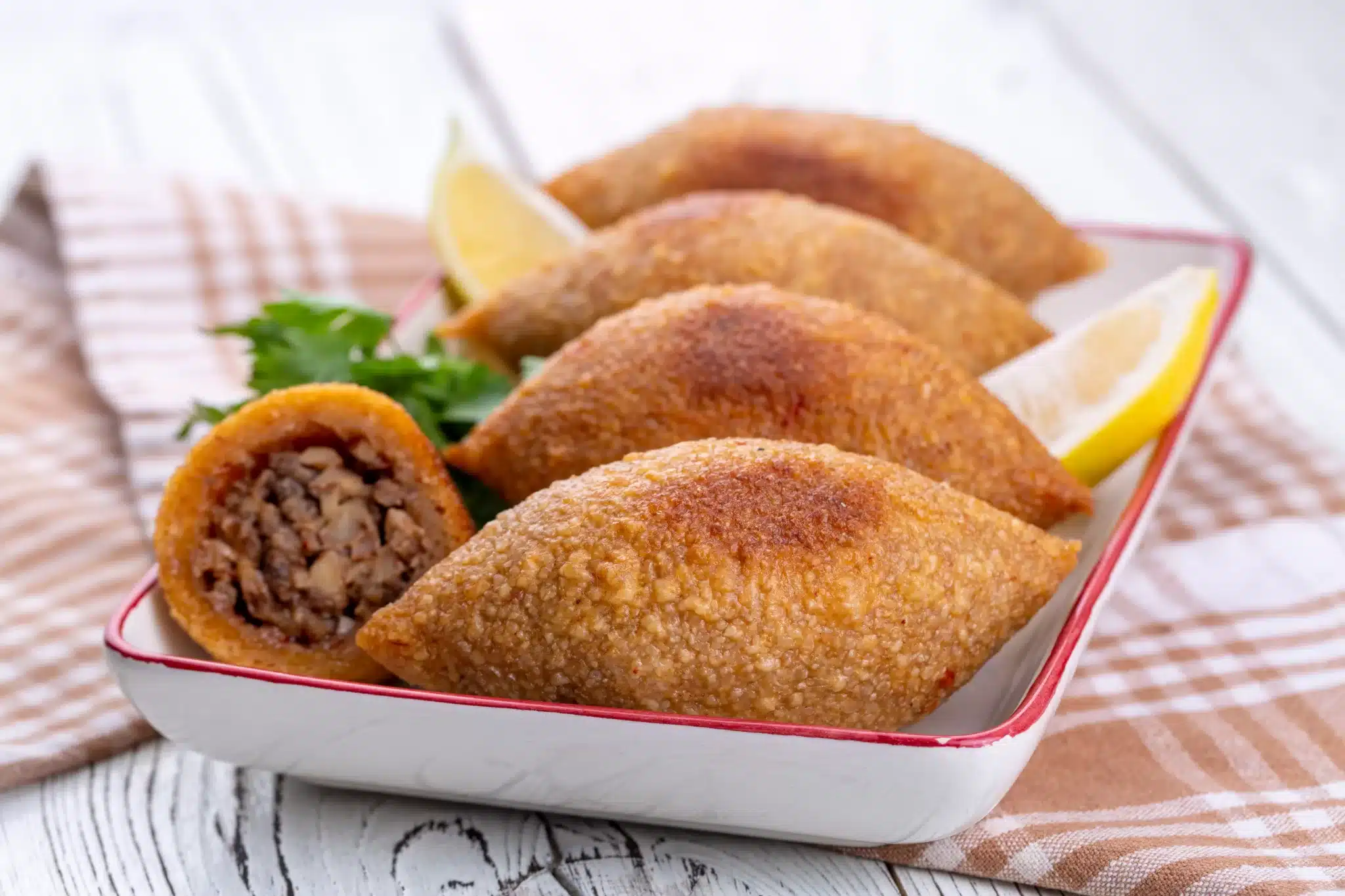 A portion of kibbeh garnished with parsley and lemon slices.