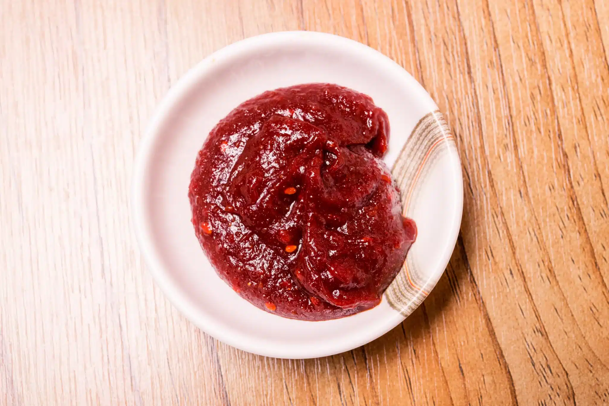 Aerial view of a bowl with kanzuri sitting on a wooden table.