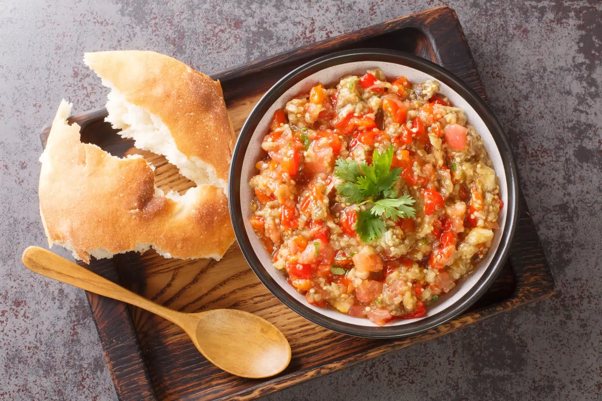Overhead view of a wooden tray featuring a plate of tasty kyopolou served with a bread piece.