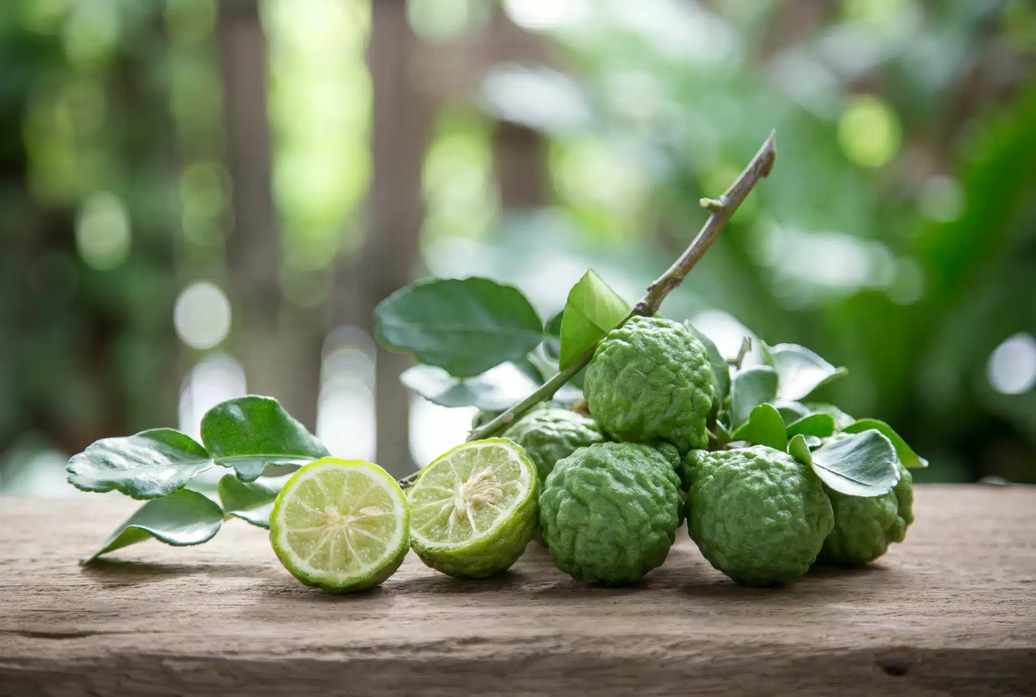 A blurred background featuring a bunch of Kaffir limes sitting on a wooden board.