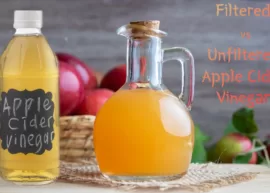 A couple of containers of either filtered or unfiltered apple cider vinegar, accompanied by a basket overflowing with apples.