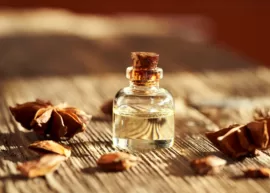 A rustic wooden table showcasing a bottle of anise extract surrounded by starry anise.