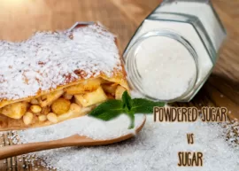 A piece of apple strudel sprinkled with powdered sugar next to an overturned jar spilling sugar.