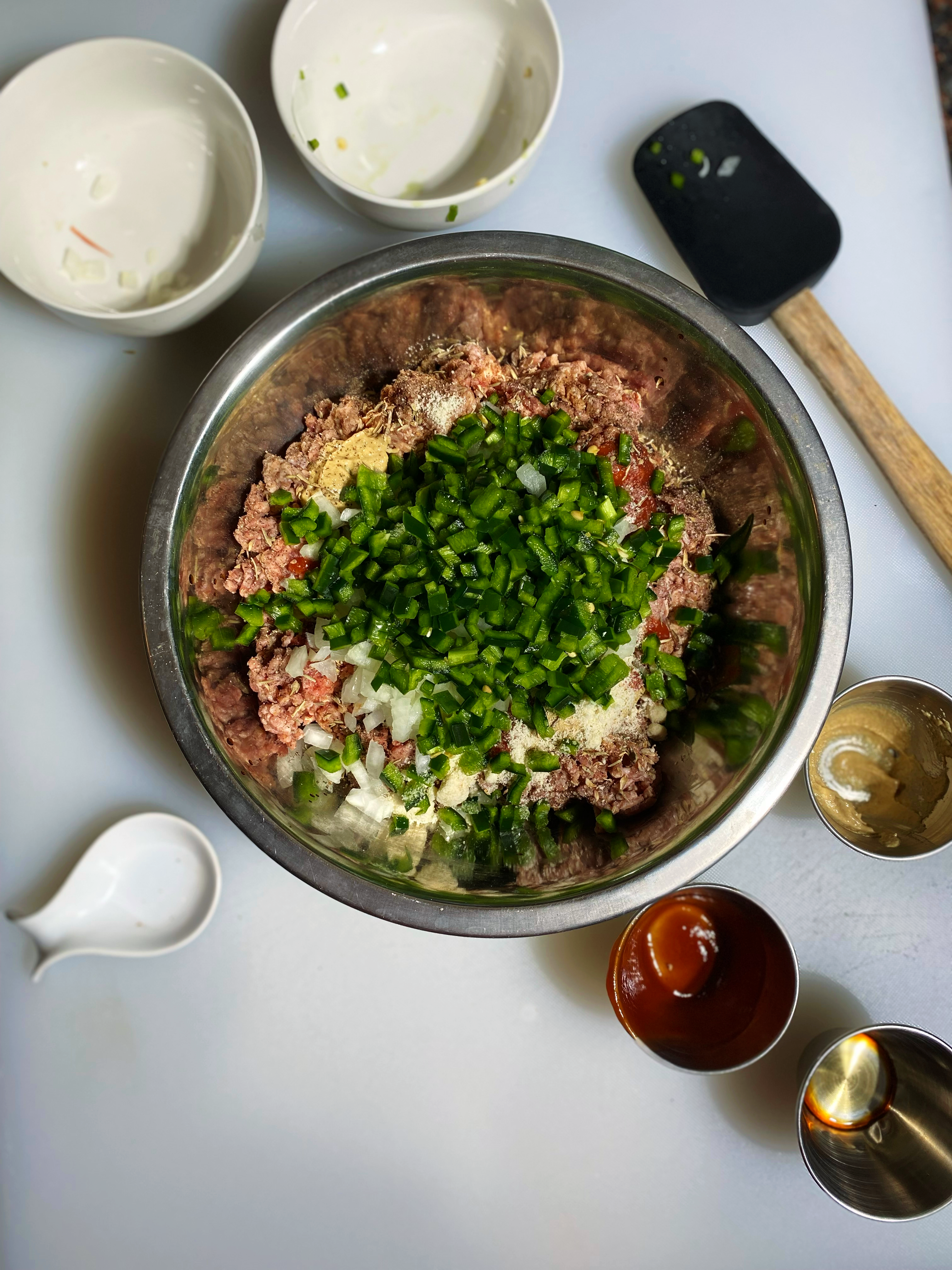 Overhead shot of the onions and peppers added into the bowl of meat.