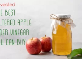A jar of filtered apple cider vinegar encircled by a few apples. The text reads, "Revealed: The Best Filtered Apple Cider Vinegar You Can Buy."