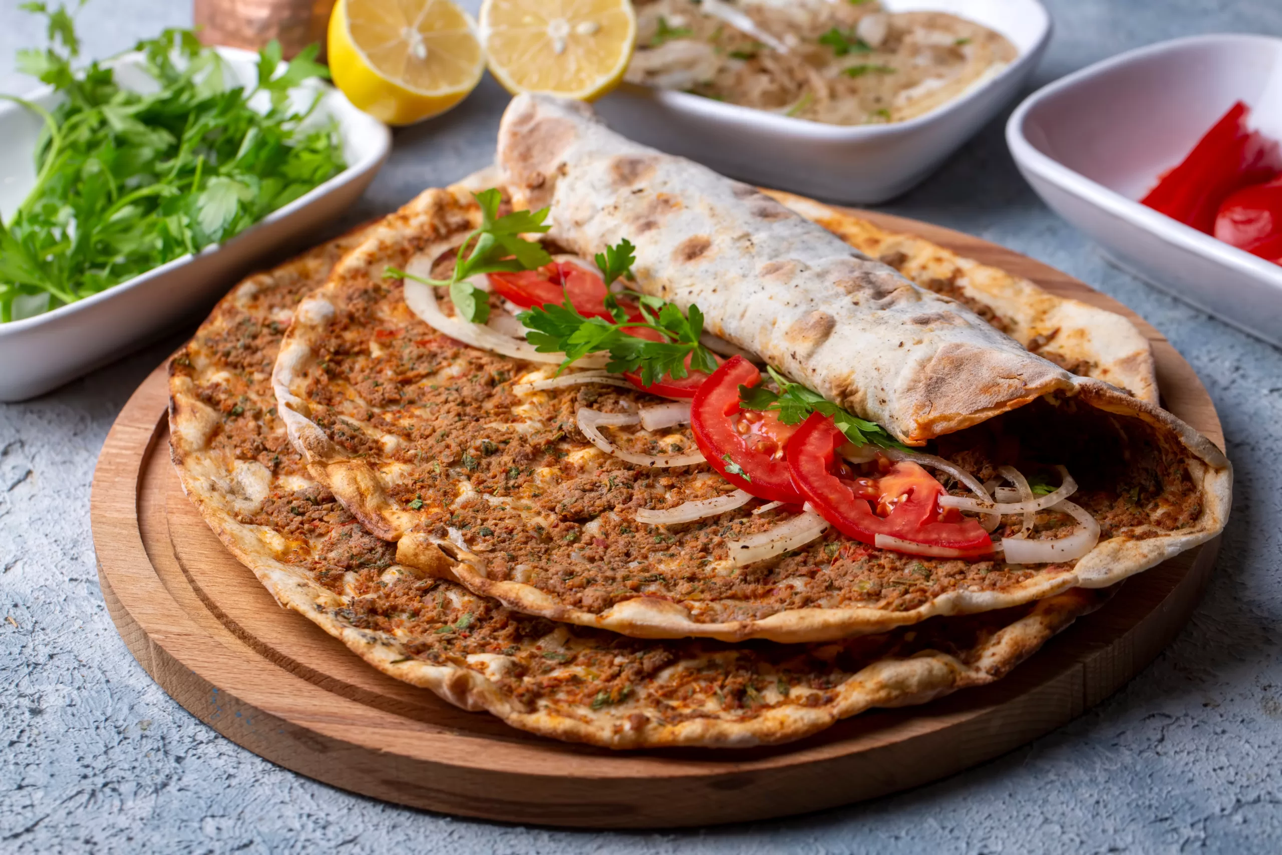 A few delicious lahmacuns resting atop a chopping board.