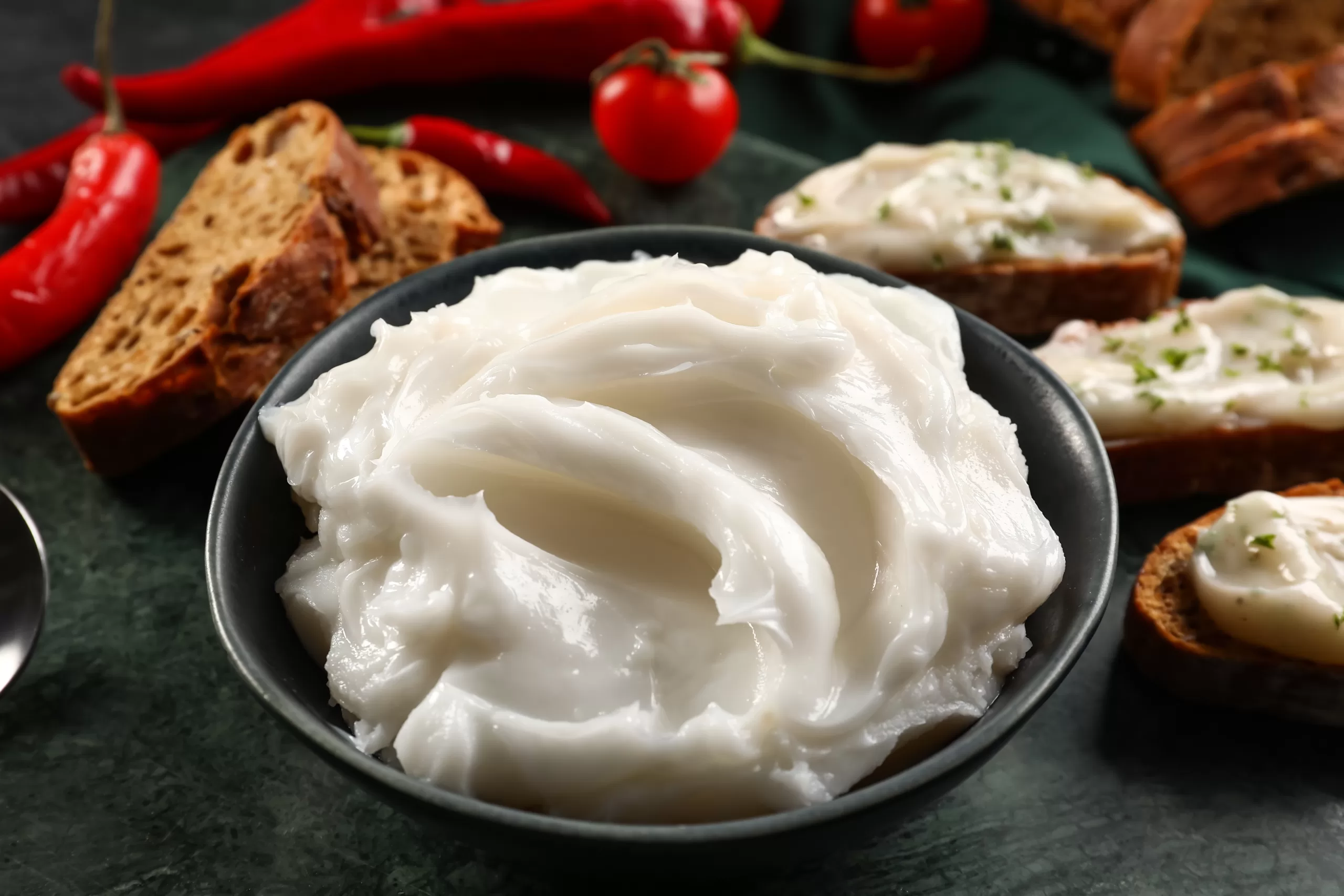 Lard contained in a bowl and spread over some bread pieces. 