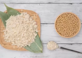 Tofu crumbles on bamboo tray, soybeans in bowl, spoon with crumbles.
