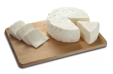 Round cheese with slices on a wooden board