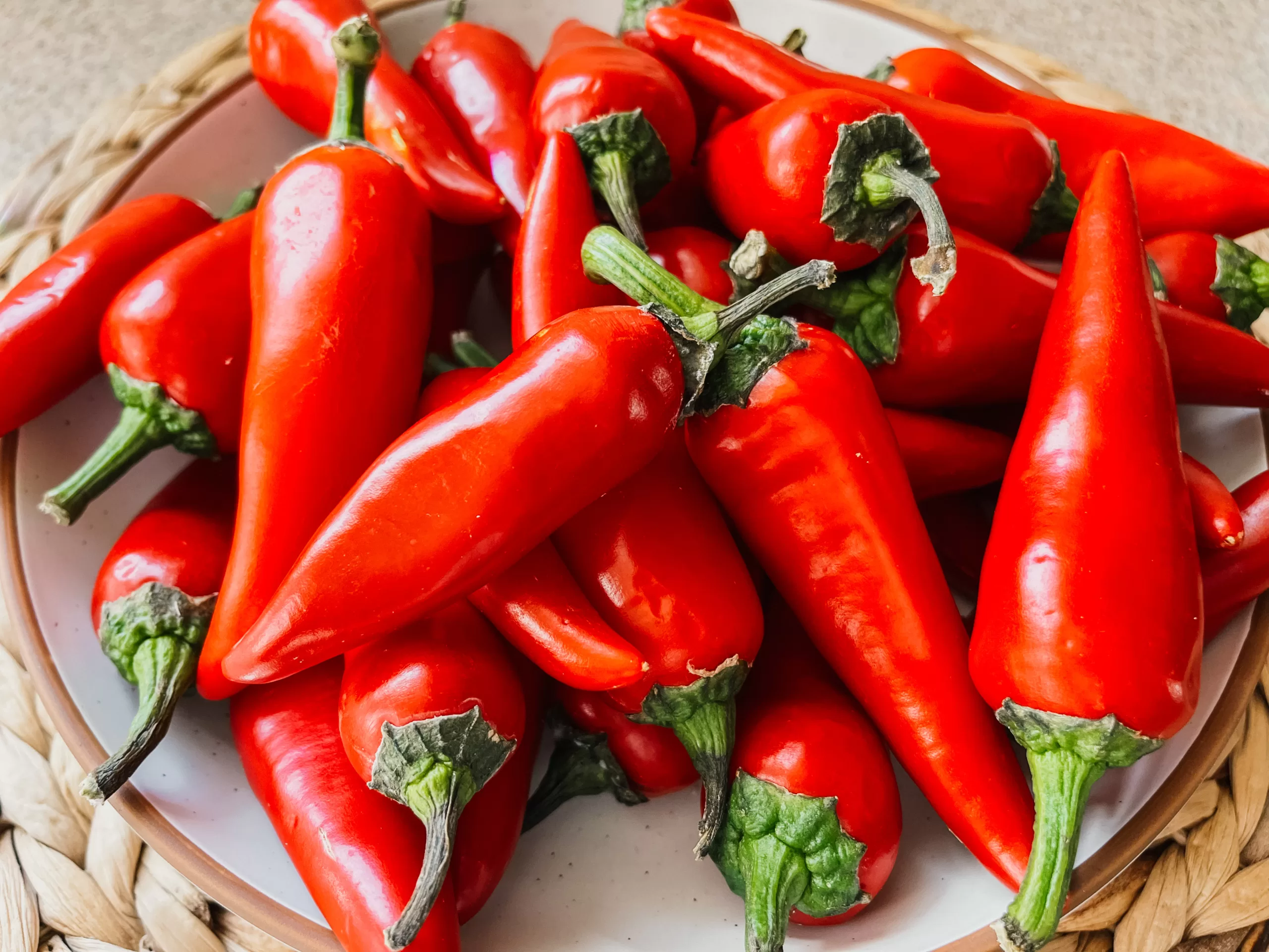 A close-up image of a bowl of red jalapeño peppers.
