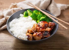Plate of teriyaki chicken with rice and broccoli and chopsticks
