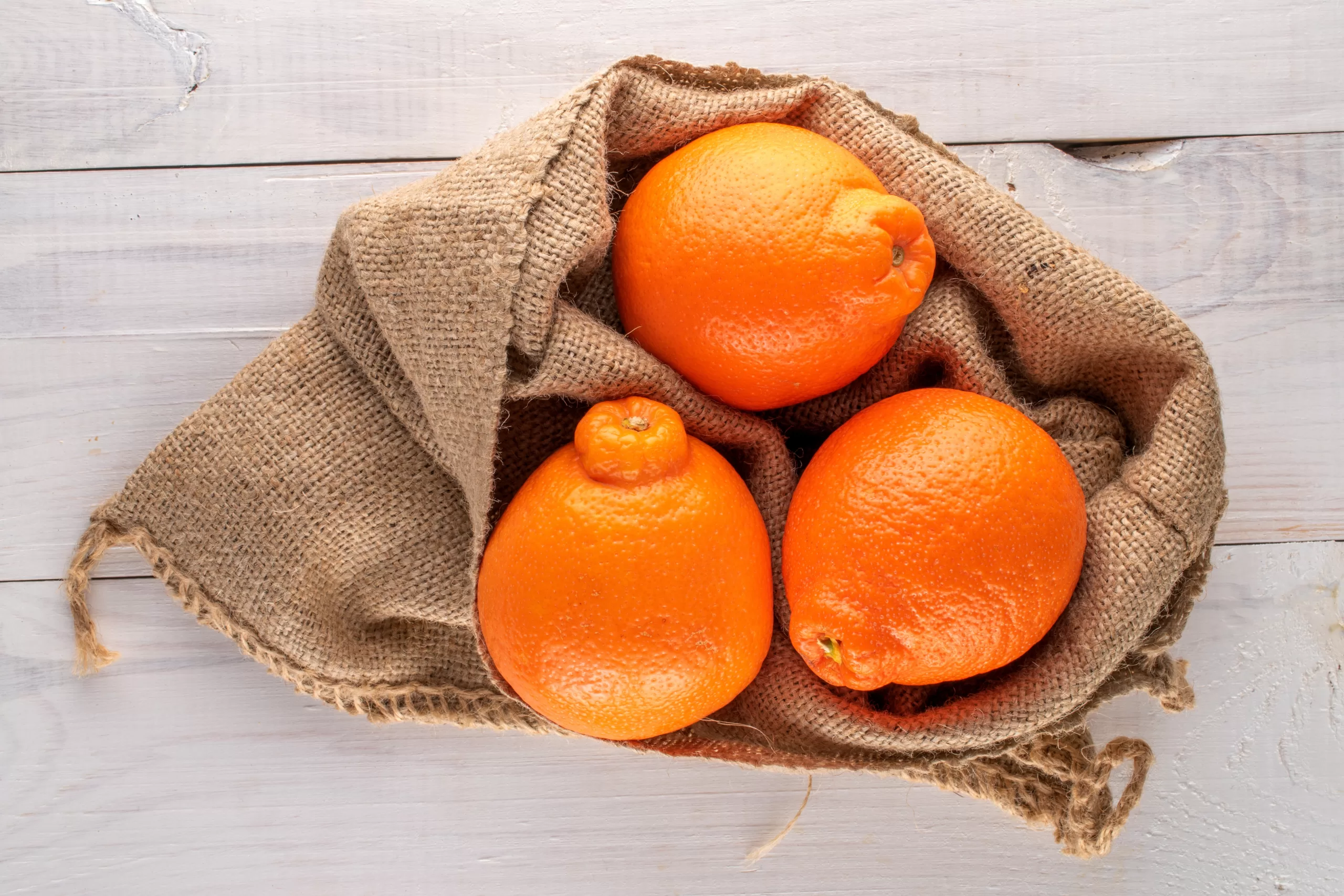 Aerial view of a burlap sack containing tangelos. 