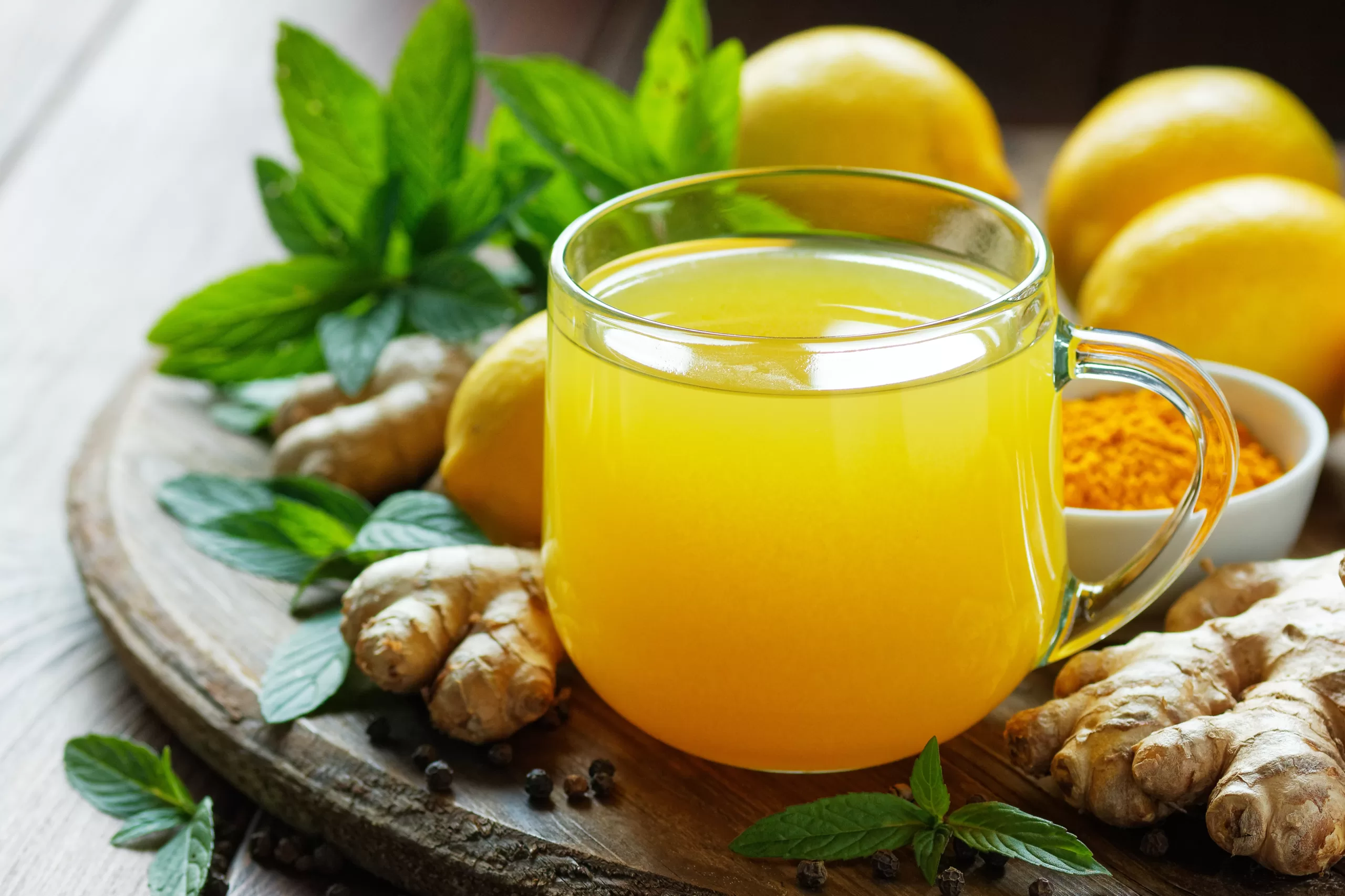 Turmeric winter hot tea with ginger, lemon, mint, and spices on a rustic wooden background,