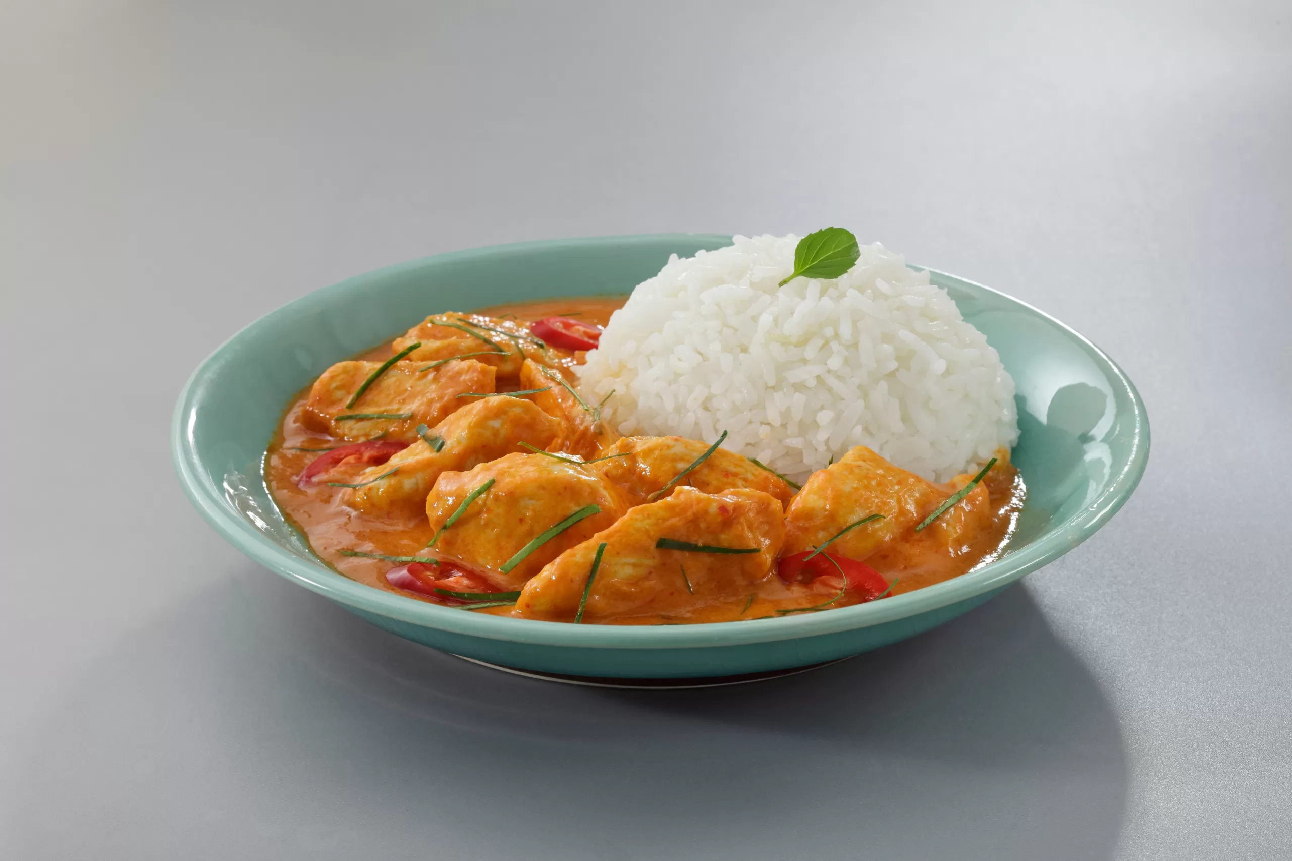 An isolated portion of Thai curry chichen with rice. 