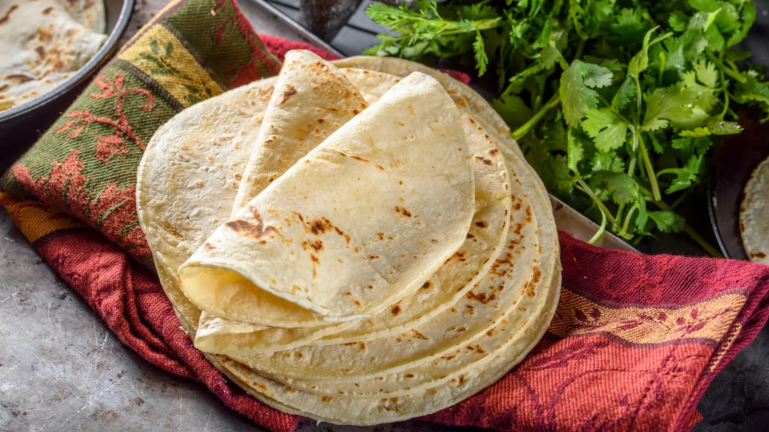 A pile of freshly cooked tortilla resting on a colorful napkin. 