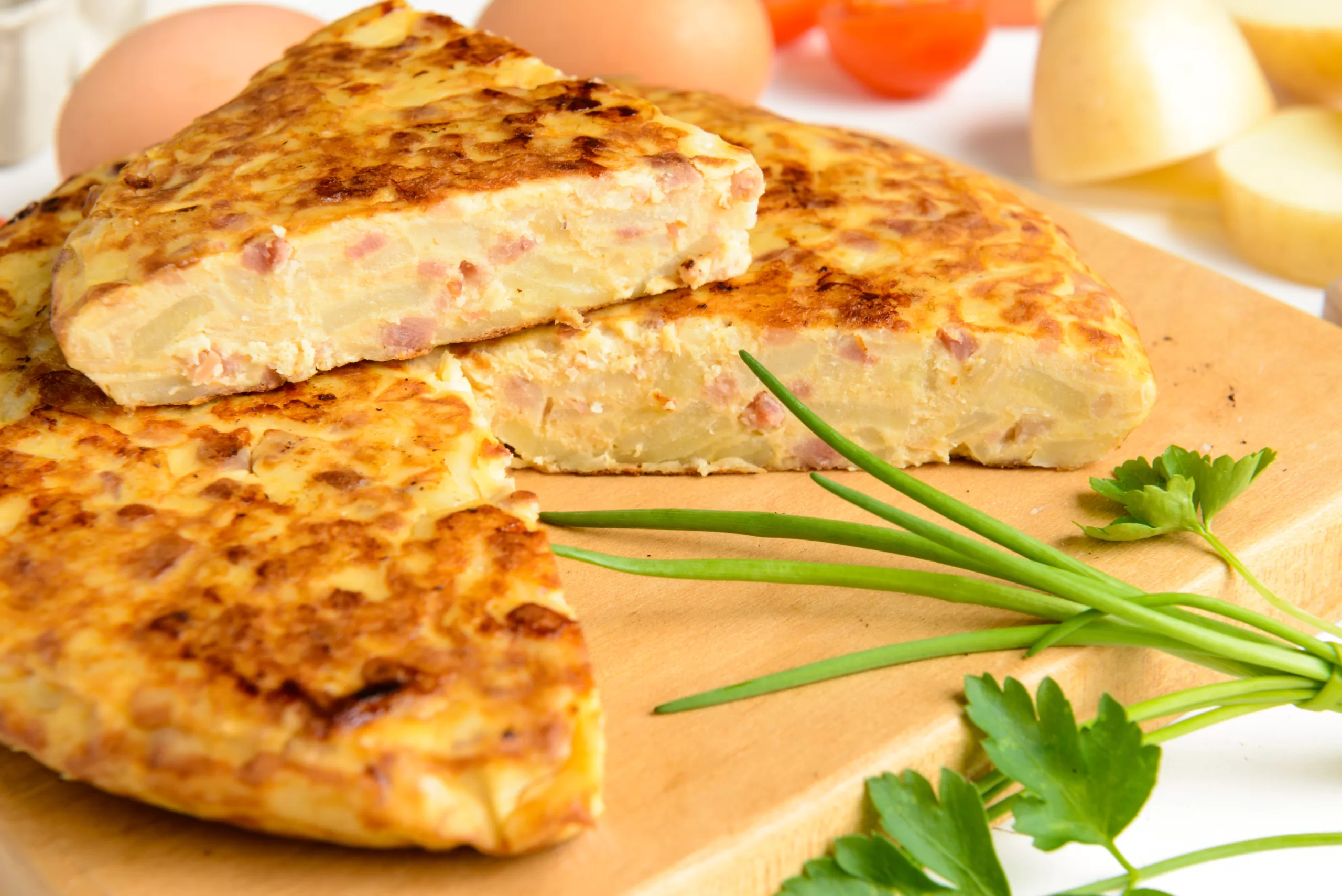 A cut tortilla Española resting on a wooden board. 