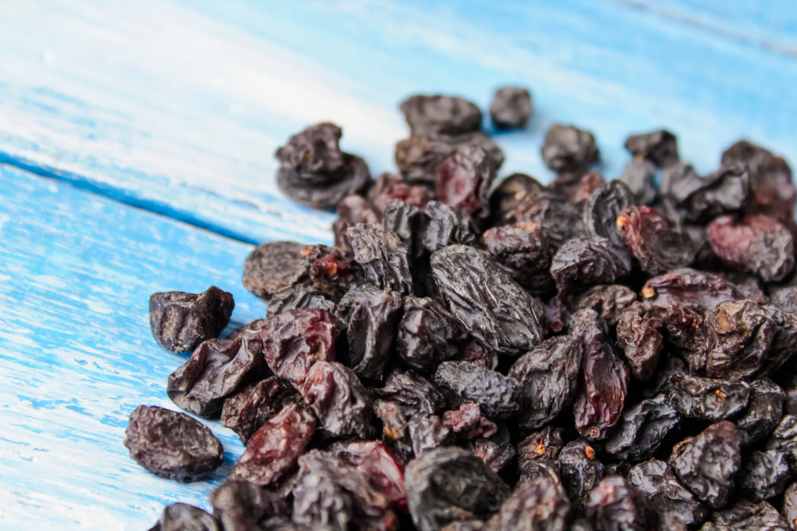 A weathered blue table displaying a mound of zante currants.