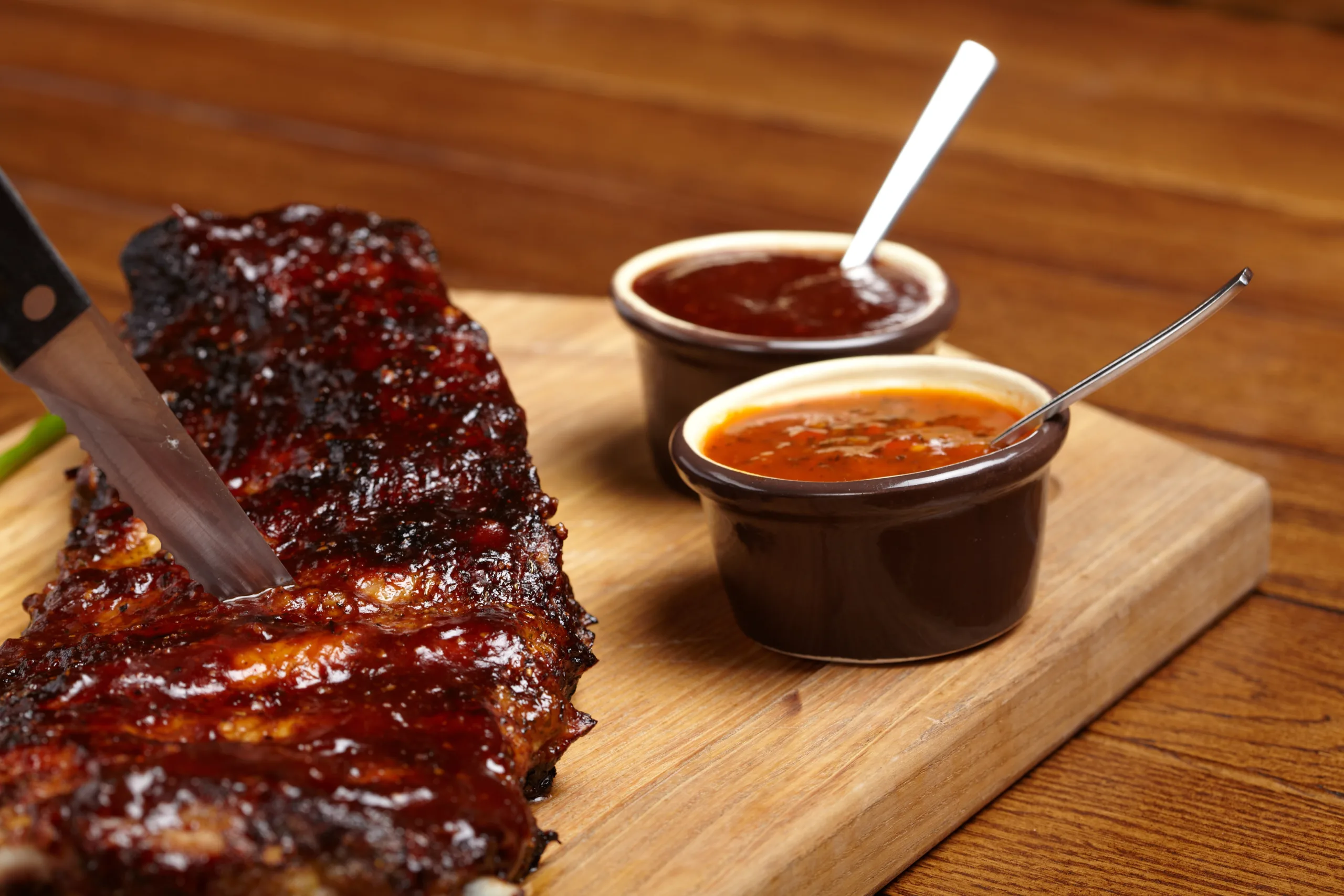 Delicious barbecue ribs accompanied by barbecue and zesty BBQ sauces.