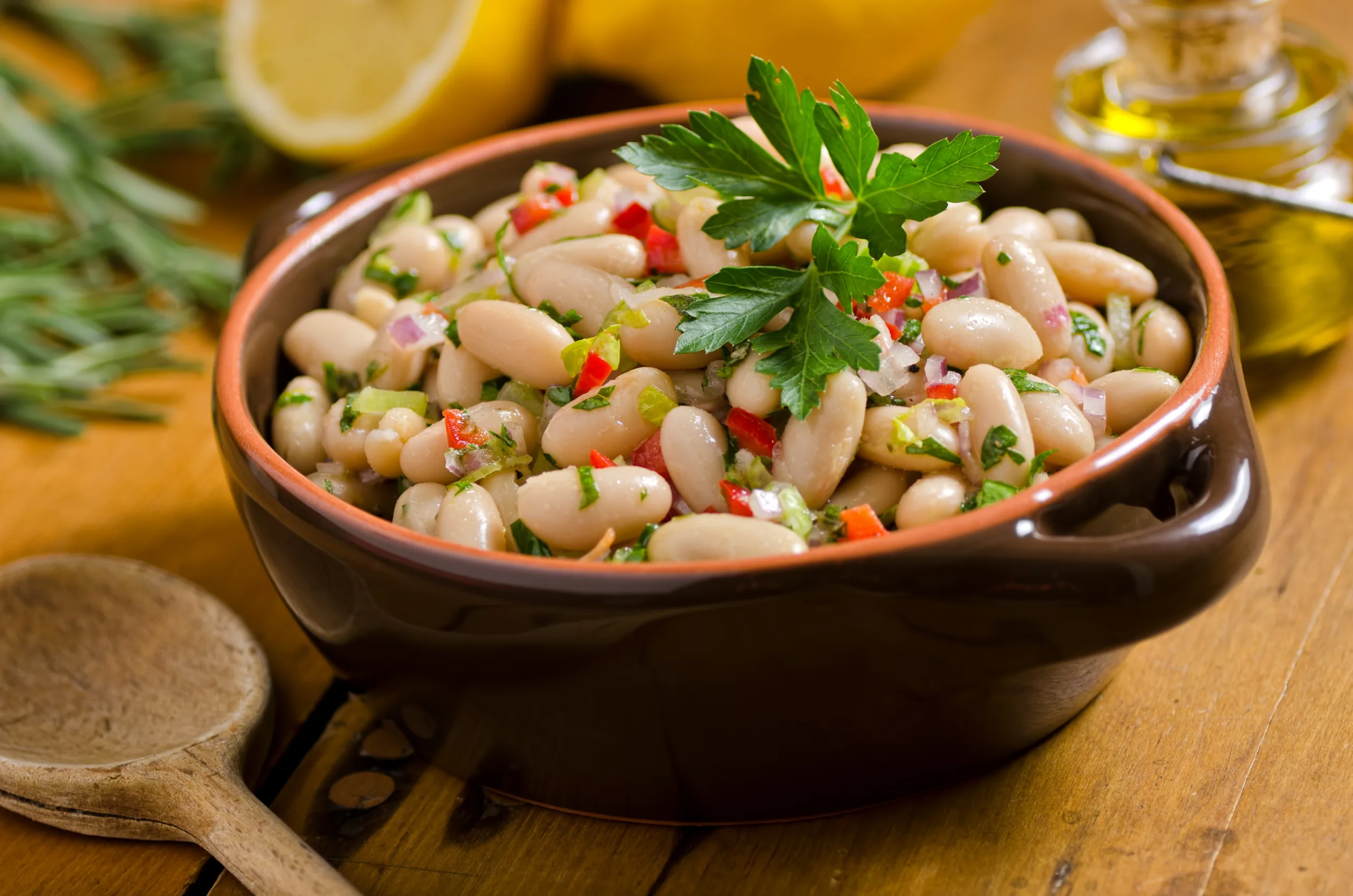 A clay bowl heaped with white bean salad.