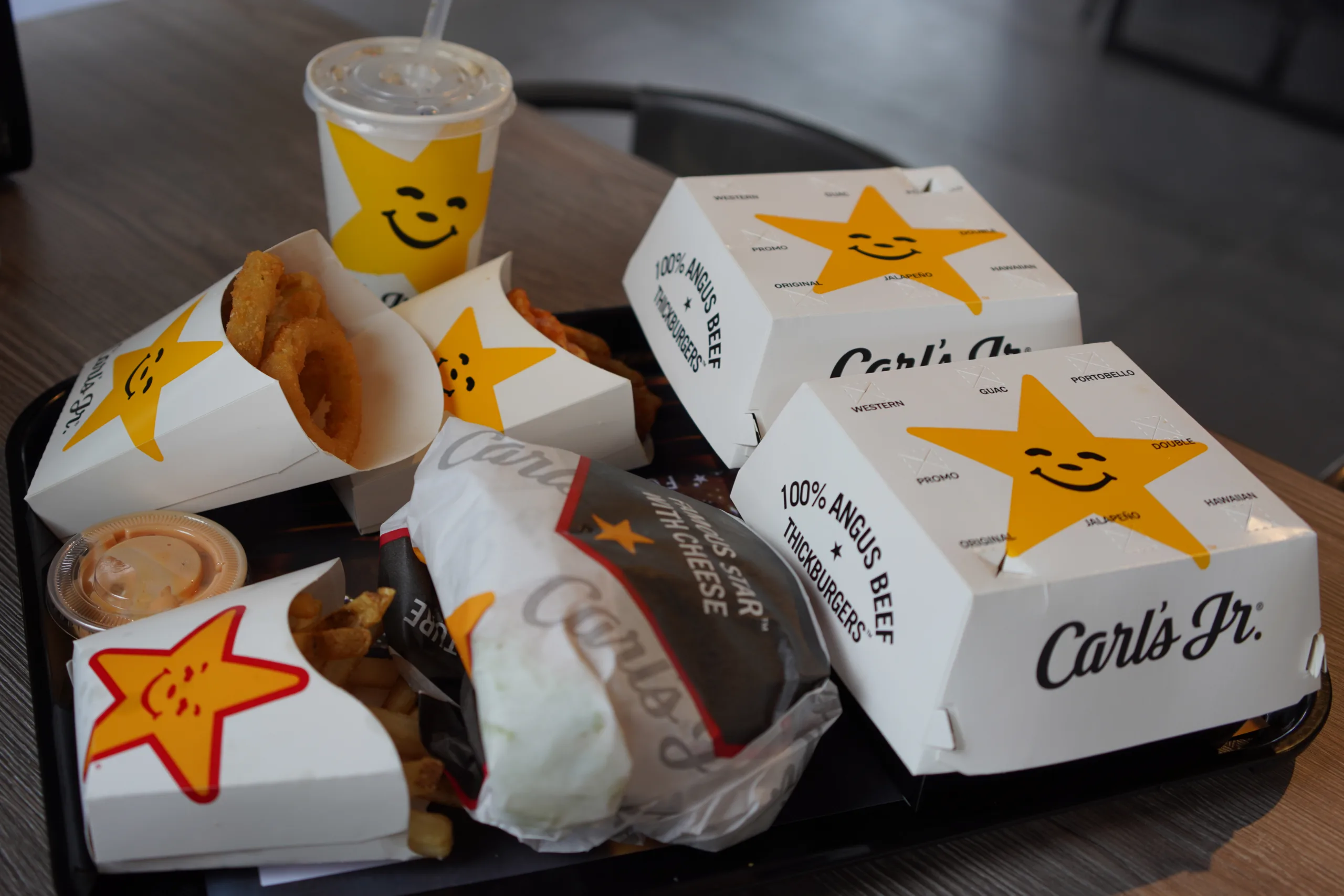 A close-up shot of western bacon cheeseburgers, onion rings, and French fries at a Carl's Jr. restaurant.