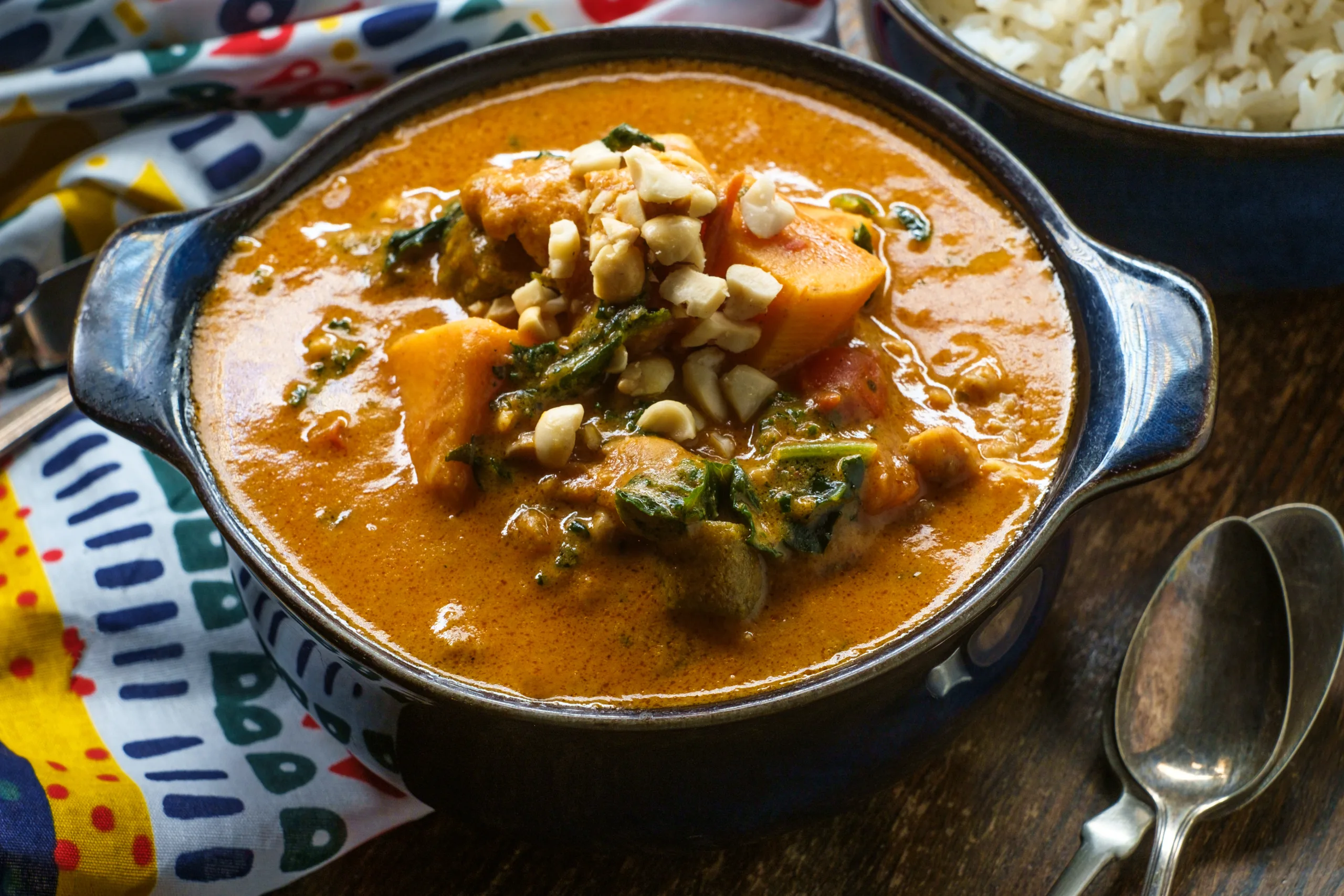 A portion of traditional West African peanut stew sitting on a wooden table.