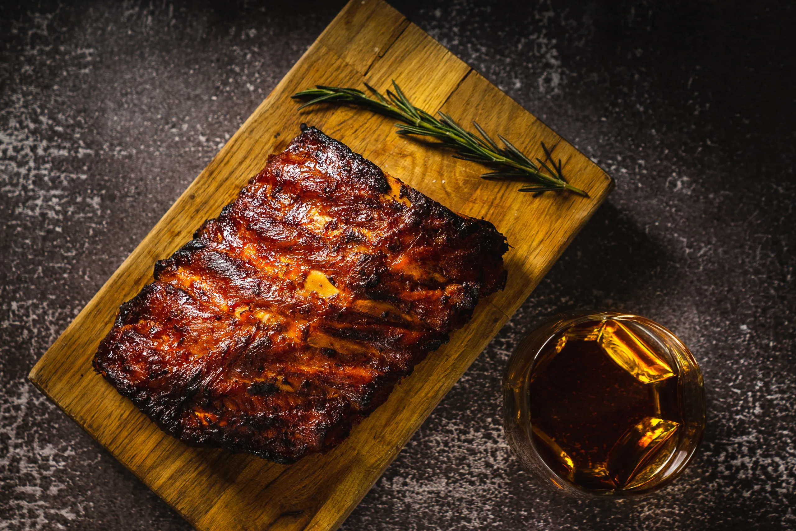 Aerial view of a wooden board featuring delicious whisky BBQ ribs.