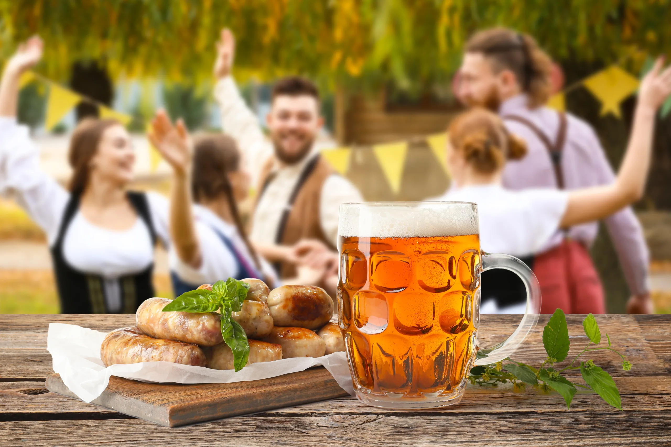 Fresh beer and wurst sausages on an outdoor table during Oktoberfest festival celebration.