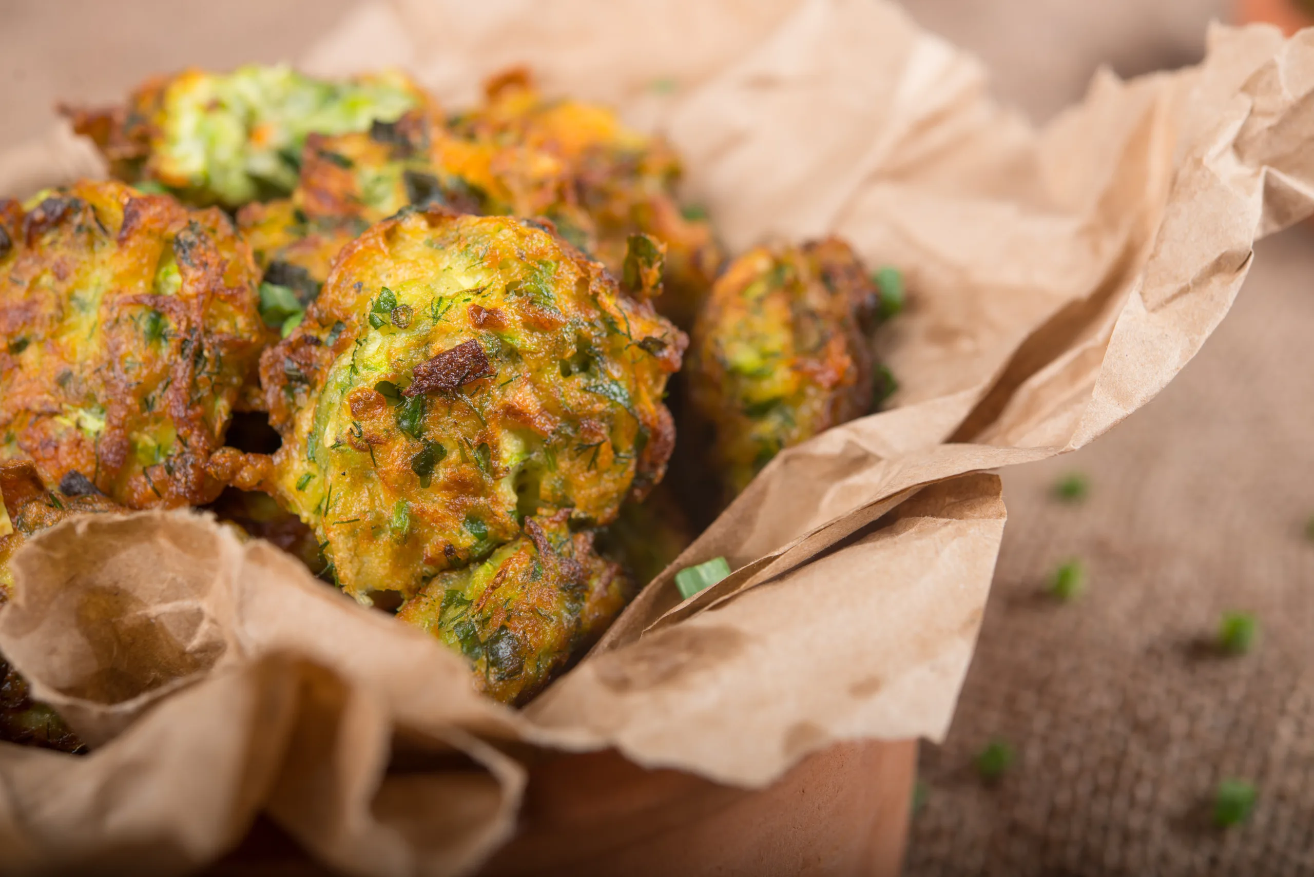 A paper bag brimming with zucchini fritters. 