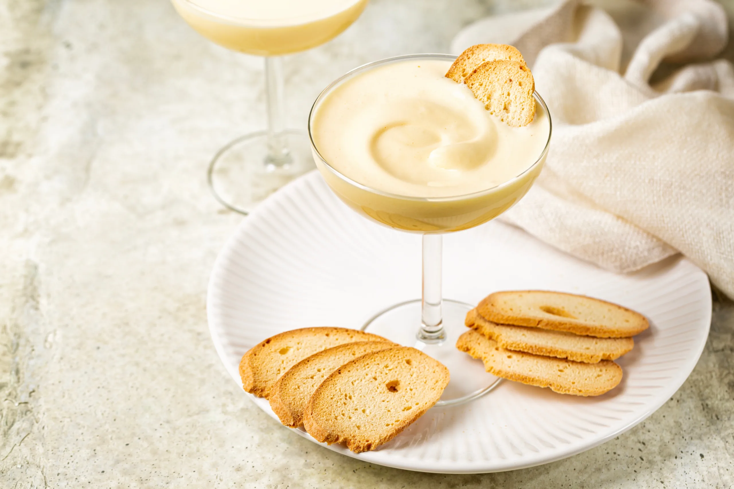 A pair of servings of zabaglione, accompanied by Baicoli cookies. 