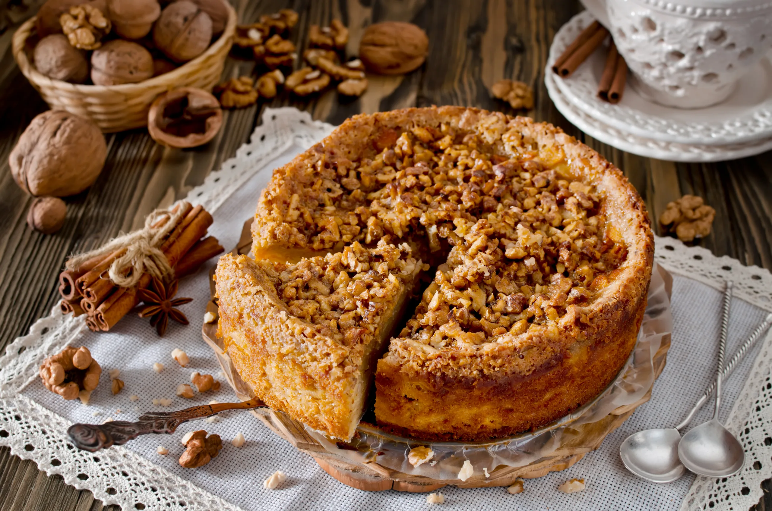 A wooden table showcasing a partially cut walnut pie encircled by some of its ingredients.