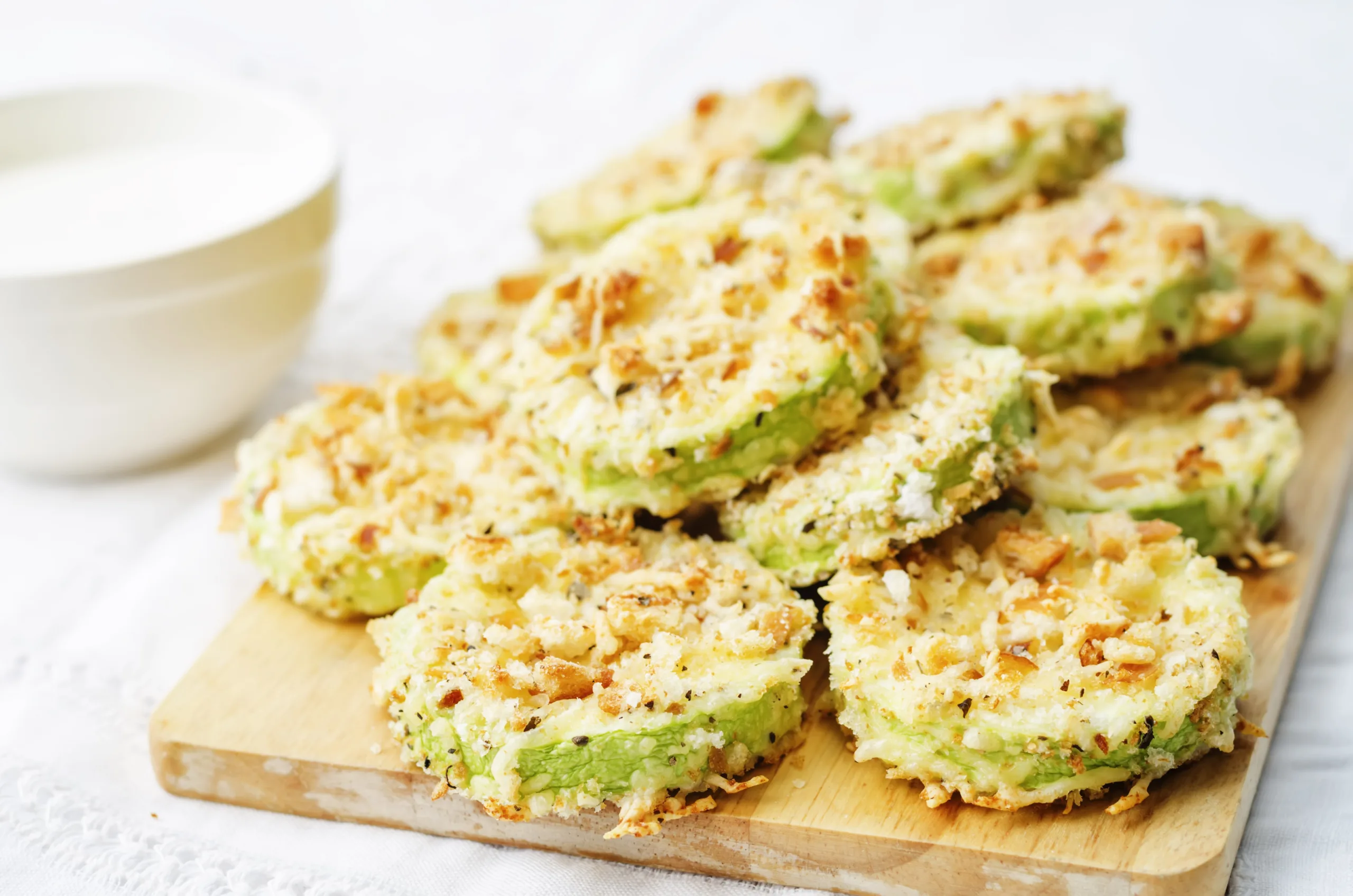 A heap of freshly cooked zucchini parmesan crisps resting on a chopping board.
