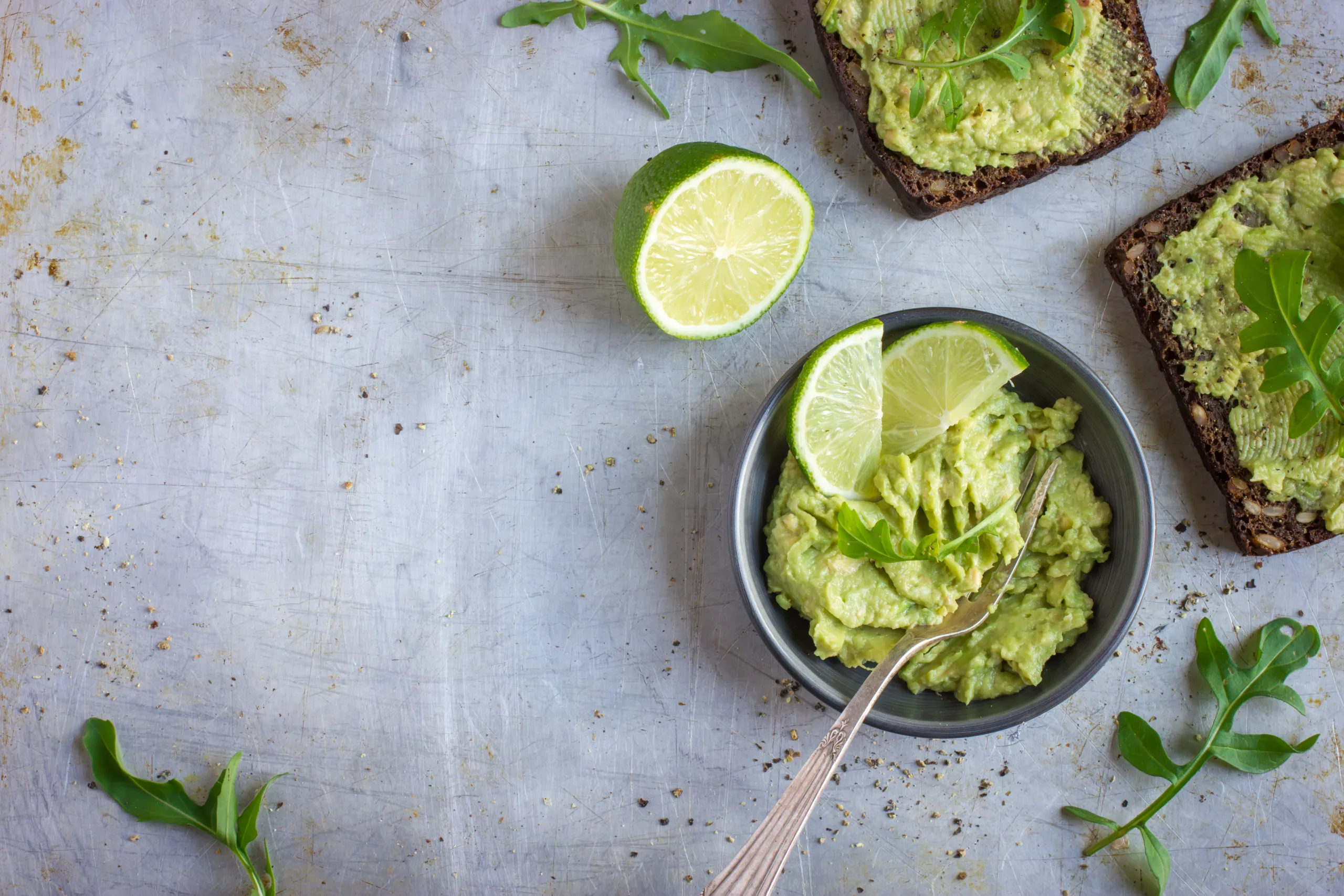 Aerial view of a concrete table showing zaboka choka in a bowl and smeared on rye bread slices. 