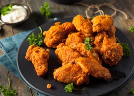 Fried chicken with leafy greens on a black plate