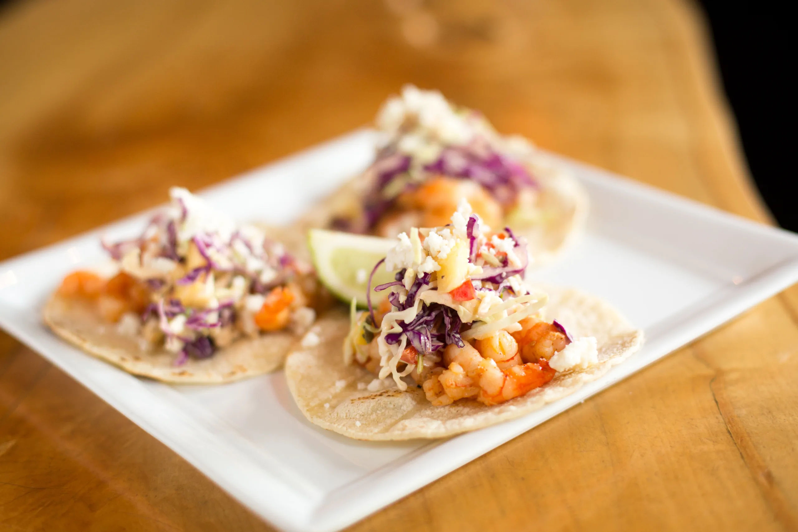 A few zesty fish tacos served on a square-shaped plate.