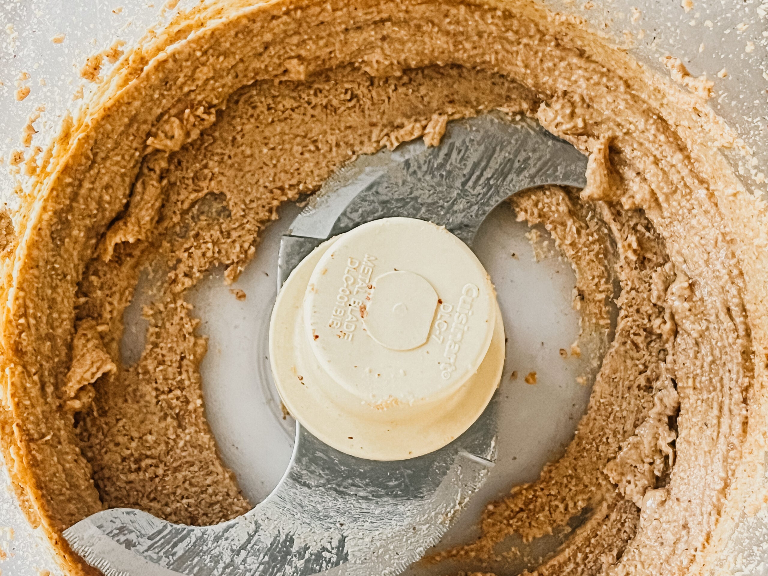 A close-up of a food processor with creamy nut butter.